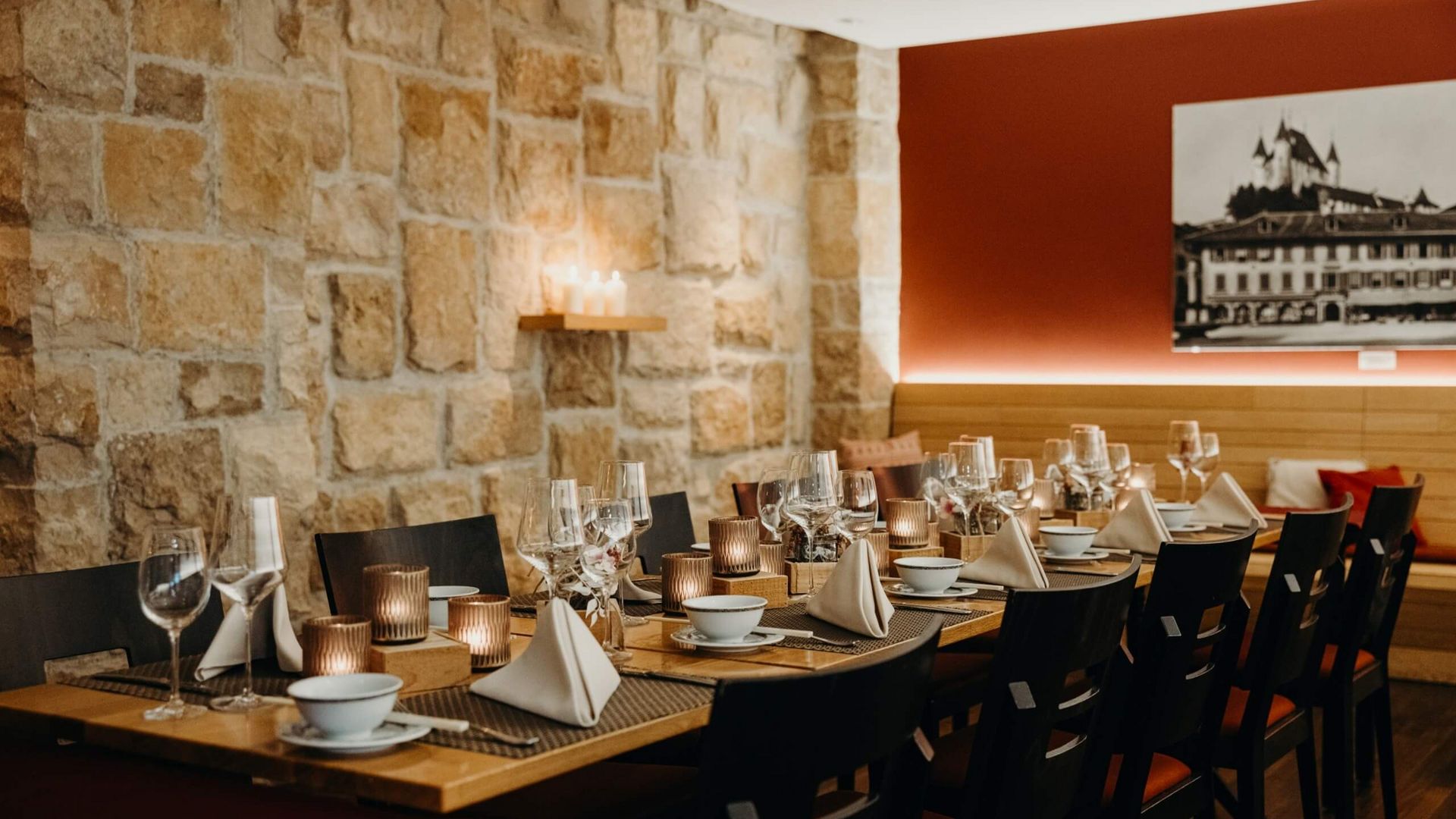 Gedeckter Tisch im Restaurant des Hotels Krone in Thun mit einem alten Bild des Rathausplatzes in Thun an einer roten Wand