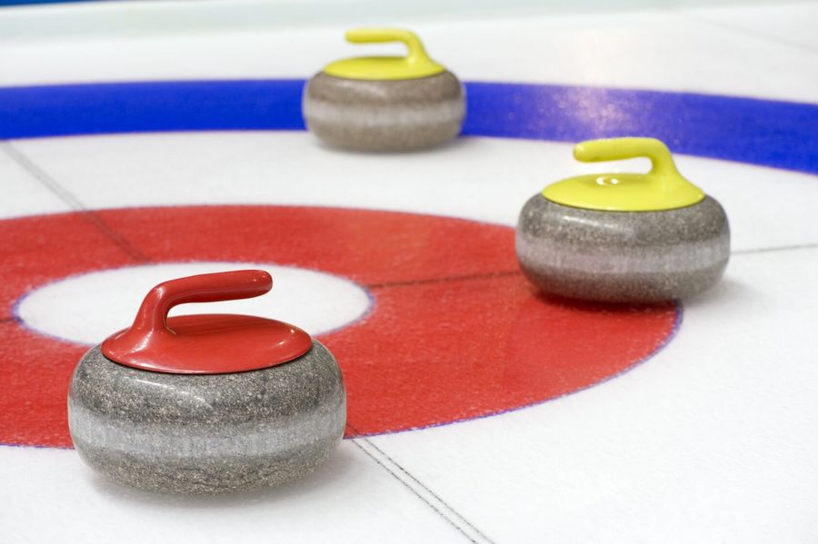 Drei Curling Steine auf dem Eis im Zielraum